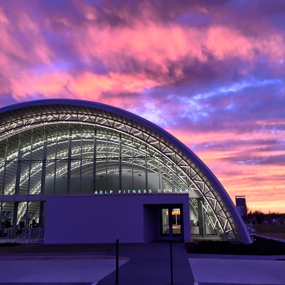 steel arch building against pink and purple sunset