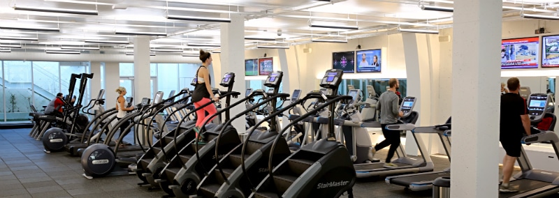 gym with people working out on elliptical machines and treadmills