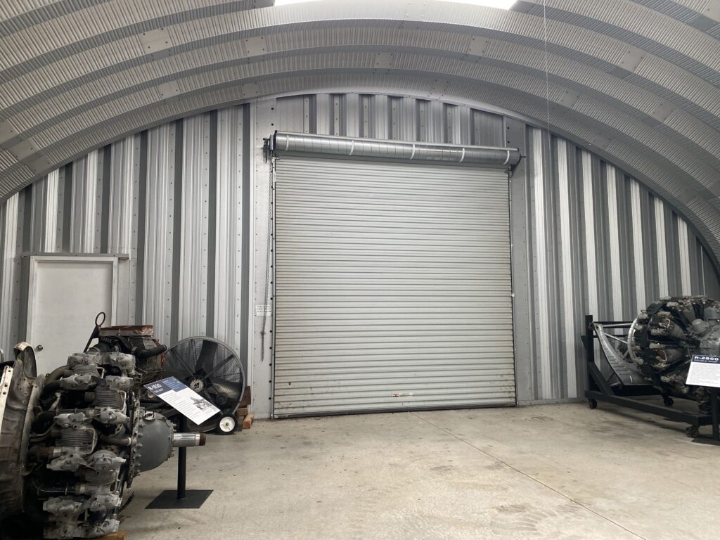 Inside of Quonset hut, metal endwall, rolling door, aircraft engines