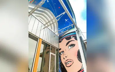 Steel arch awning over store entrance with locally painted murals underneath.