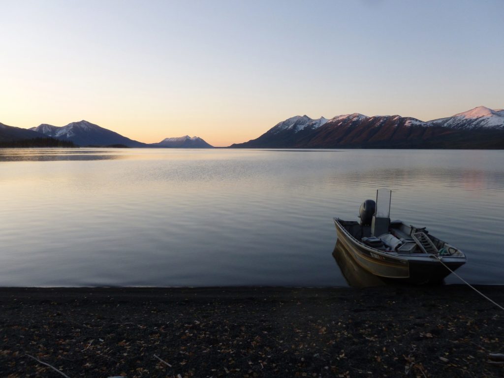 Lake with boat on shore at sunset