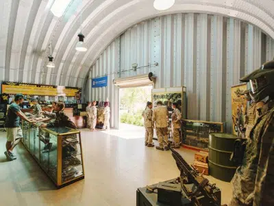 Inside Quonset building, metal endwall, handing overhead lights, rolling door, military personnel.